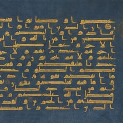 Gold Kufic letters in long horizontal strokes on parchment dyed deep indigo, with a small gold verse marker at the right edge.