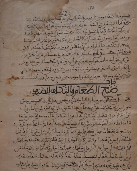 A worn brown page of Arabic in rounded Maghrebi script, with chapter headings written in larger, bolder letters.