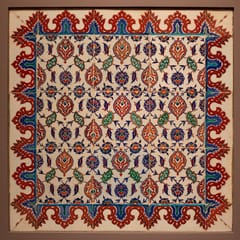 A square panel of white Iznik tiles patterned with red, cobalt, and green flowers and leaves inside a scalloped red border.
