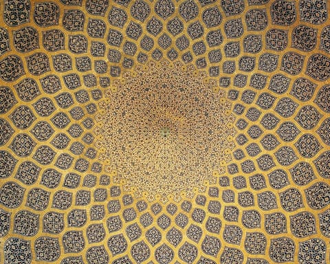 Looking straight up into a tiled dome: rows of lemon-shaped medallions in gold and blue grow smaller as they spiral toward a bright center.