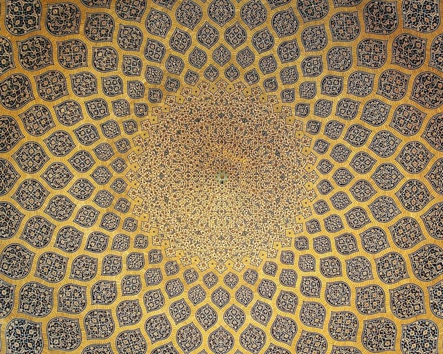 Looking straight up into a tiled dome: rows of lemon-shaped medallions in gold and blue grow smaller as they spiral toward a bright center.