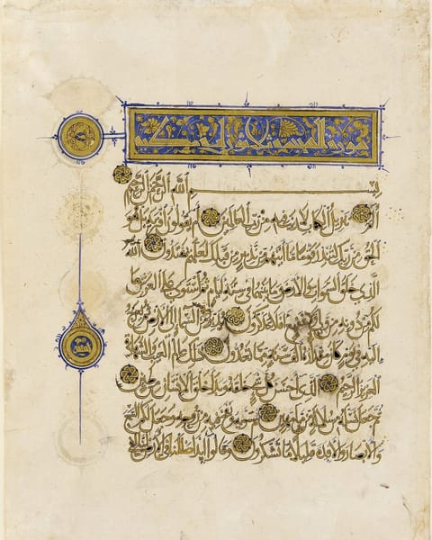 A cream page of flowing gold script outlined in black, with gold verse rosettes, a blue and gold heading panel, and round gold medallions in the margin.