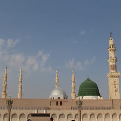 The green dome over the Prophet's resting place rises beside a silver dome and tall white minarets above the arcades of the mosque in Medina.