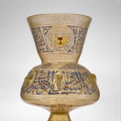 A tall enameled glass lamp with a flared neck, its body ringed with large blue Arabic letters and a red and gold emblem.